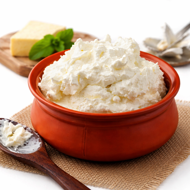 Red bowl filled with ricotta cheese on a white background
